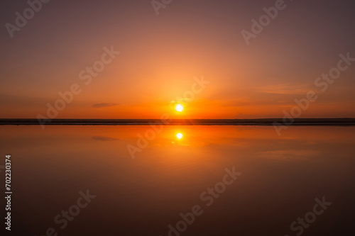 Sunset or sunrise sky. Clouds over water. Golden Dawn. Dramatic coast nature background. Beautiful sea beach at sunset. Morning shoreline sunlight.