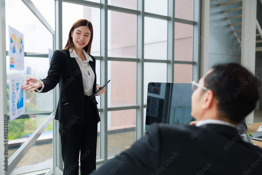 Strategic Corporate Presentation: Asian Businesswoman Presents to Management in Modern Office Setting Strategic Corporate Presentation: Asian Businesswoman Presents to Management in Modern Office Setting