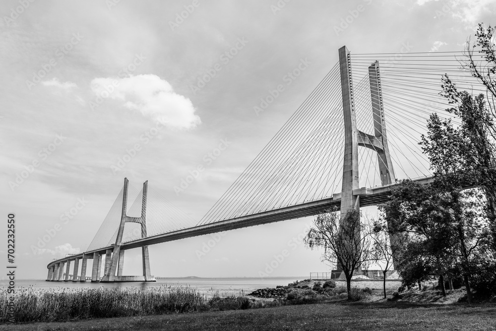 Obraz premium Vasco da Gama bridge in Lisbon, Portugal; cable stayed bridge flanked by viaducts and rangeviews that spans the Tagus river in Parque das Nacoes, the second longest bridge in Europe in black and white