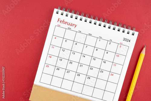 February 2024 desk calendar and pencil on red background.