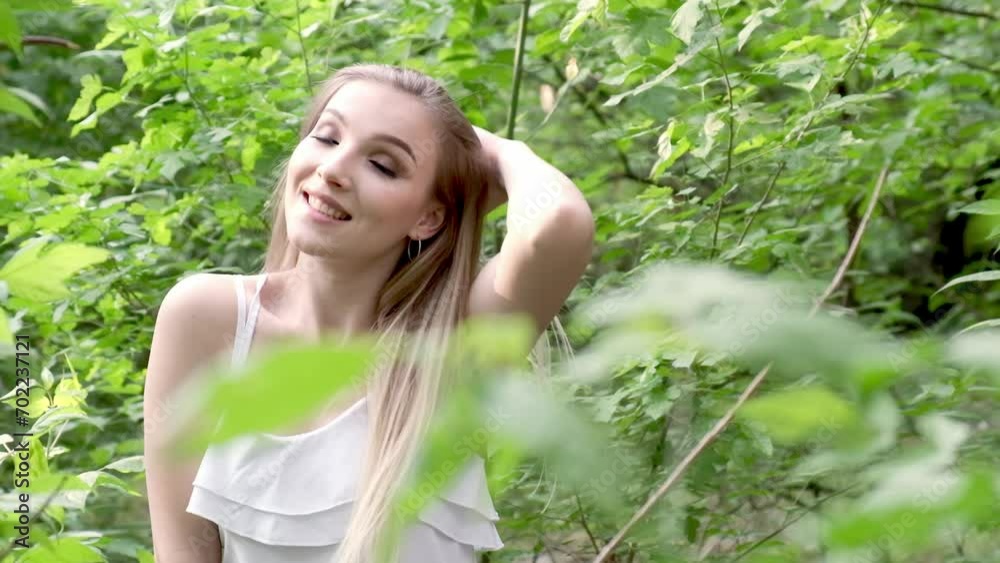 A beautiful lady walking through a summer park enjoys the green sunny nature close-up. Gorgeous girl walking through the greenery of the garden. The concept of a happy and carefree life. A beautiful lady walking through a summer park enjoys the green sunny nature close-up. Gorgeous girl walking through the greenery of the garden. The concept of a happy and carefree life.