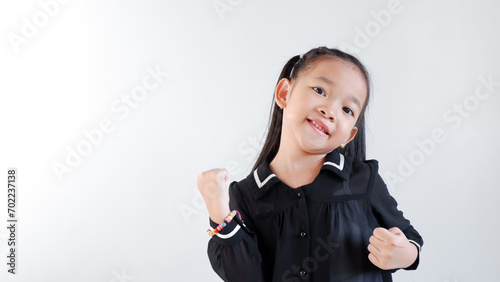 Little Asian girl wearing black outfit with healthy and victory pose over gray background.