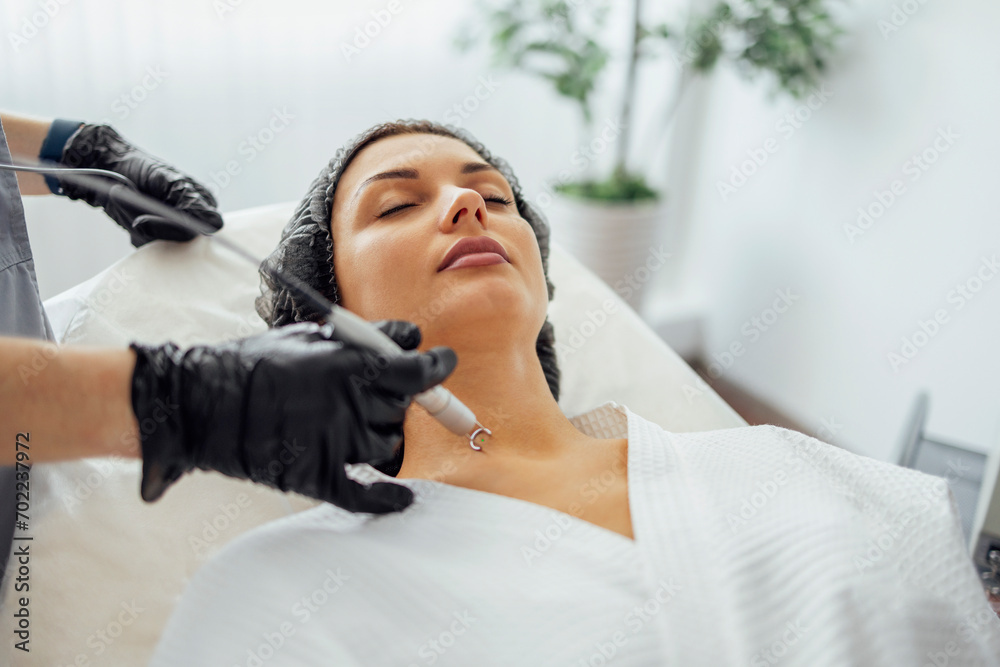 Obraz premium Beautiful caucasian young woman is doing a mole removal procedure in a modern beauty cosmetic dermatological clinic