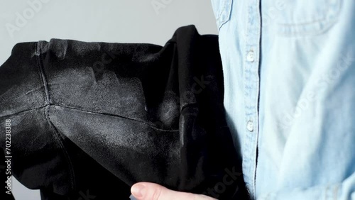 Deodorant stains on black clothes. Women's hands holding spoiled clothes. daily life stain concept.  photo
