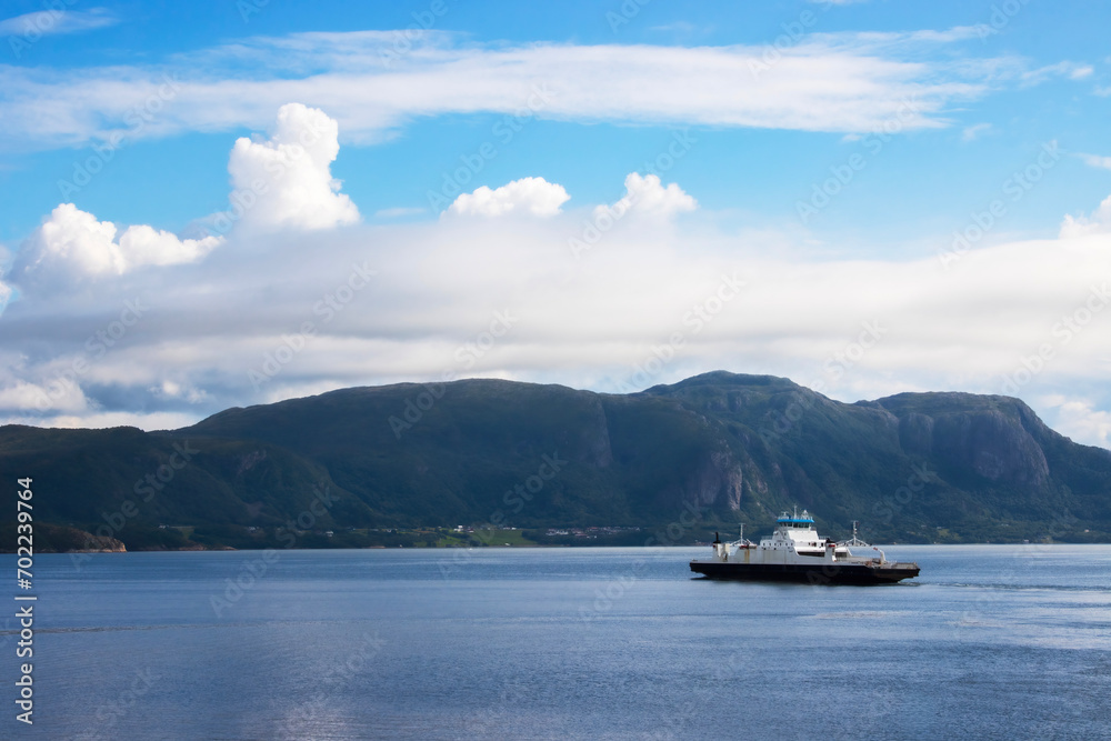 Car ferry crossing the Fjord with mountains in the background