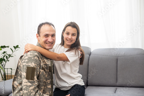 фотографія Young man in military uniform with his wife on sofa at home