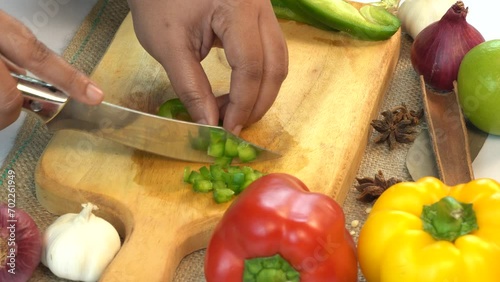 The chef cuts fresh green bell peppers to prepare a delicious salad at home.