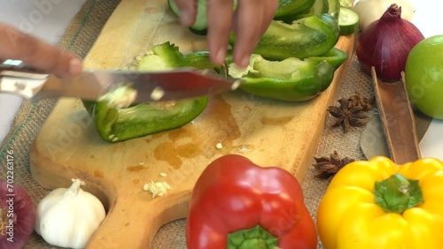 Woman cutting sweet pepper using knife on wooden cutting board. Freshly cut vegetables for fresh salad.