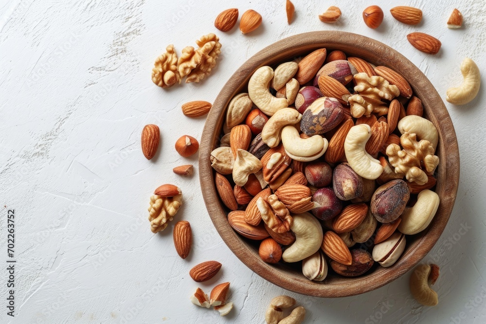 Wooden bowl with mixed nuts on white table. Healthy food and snack.