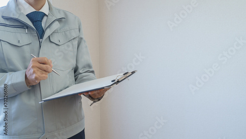 マンションの壁紙を点検する作業服の男性｜リフォーム調査・見積り　イメージ photo