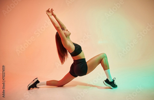 Stretching exercises. Young woman in fitness clothes is in the studio