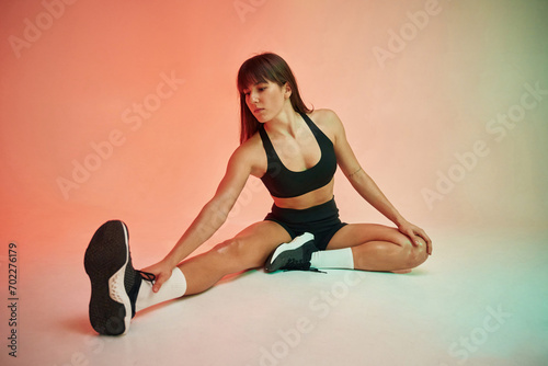 Sitting on the floor. Young woman in fitness clothes is in the studio