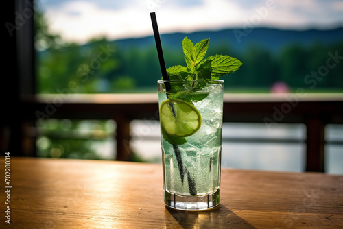 High angle view of a refreshing chilled vodka or gin cocktail Hugo on ice with fresh mint leaves and two straws on an old wooden table top in a bar or nightclub