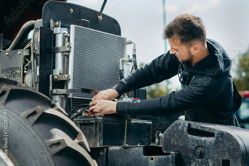 Young mechanic repair tractor outdoor 