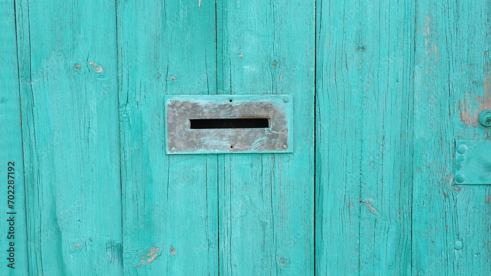 Gap in the fence designed to receive letters. The wooden fence is painted in a vibrant turquoise color Gap in the fence designed to receive letters. The wooden fence is painted in a vibrant turquoise color