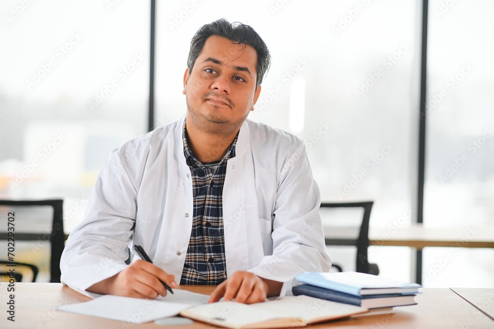Portrait of a young Indian male medical student in a white coat waving Portrait of a young Indian male medical student in a white coat waving
