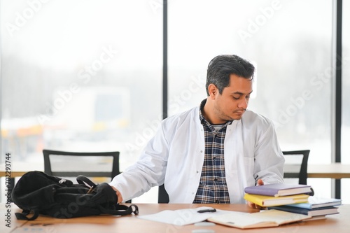 Portrait of a young Indian male medical student in a white coat waving