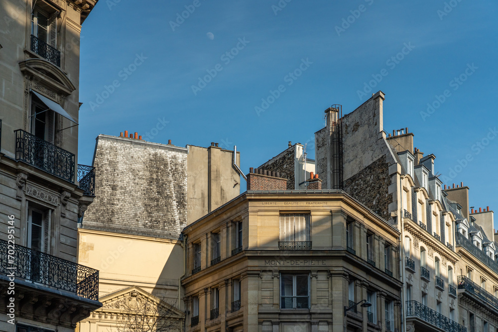 Fototapeta premium The famous gray Parisian roofs against the background of the blue sky. French architecture concept, postcard from 2024 Olympics.