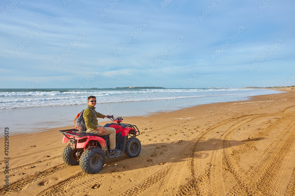 A young man explores the oceanfront on a quad bike near Essaouira, A young man explores the oceanfront on a quad bike near Essaouira,