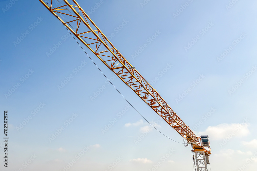 Industrial construction crane with blue sky background at building site Industrial construction crane with blue sky background at building site