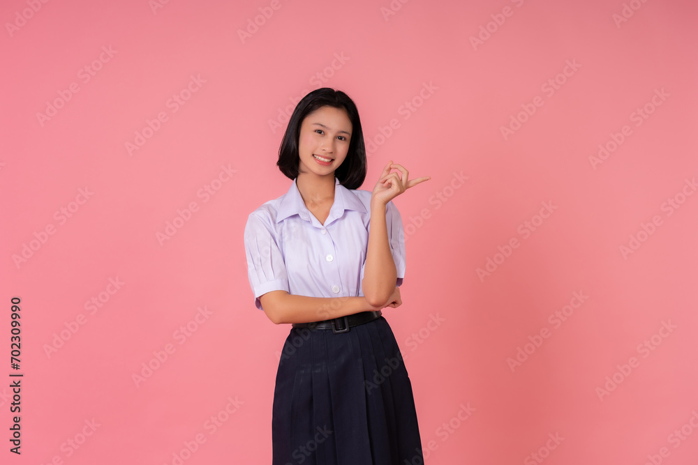 Asian teenage female student Smiling and pointing at the presentation The world's educational presenter has famous schools and tutoring institutes. Taking photos in a pink background studio Asian teenage female student Smiling and pointing at the presentation The world's educational presenter has famous schools and tutoring institutes. Taking photos in a pink background studio
