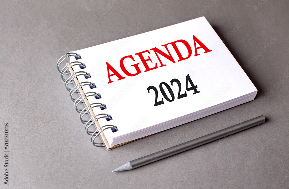 AGENDA 2024 word on notebook on grey background AGENDA 2024 word on notebook on grey background