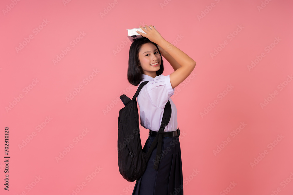 Asian female student presenter for world education Lift the textbook on your head. carrying a school bag Study at famous schools and tutoring institutes Taking photos in a pink background studio Asian female student presenter for world education Lift the textbook on your head. carrying a school bag Study at famous schools and tutoring institutes Taking photos in a pink background studio