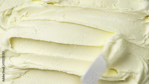 The surface of vanilla ice cream is spread with spatula