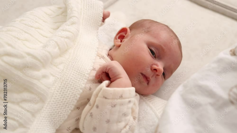 little baby baby falls asleep under a white blanket in bed. top view the kid is looking at the camera little baby baby falls asleep under a white blanket in bed. top view the kid is looking at the camera