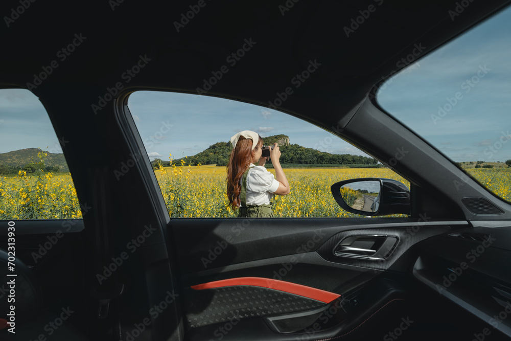 Photo taken through the vehicle showing a young woman and a mountain view.