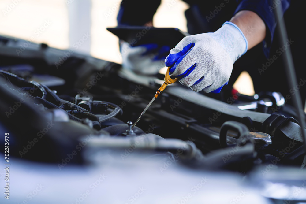 Auto mechanic checking oil in car engine Technician inspects and maintains car engines. Auto mechanic checking oil in car engine Technician inspects and maintains car engines.