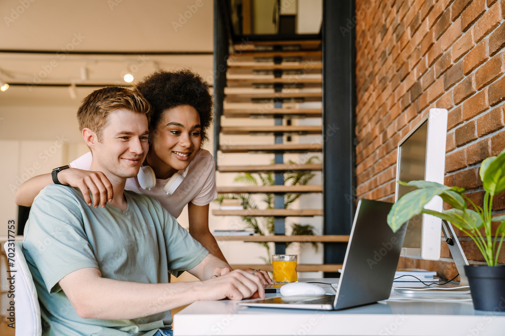 Beautiful woman hugging her boyfriend while he working on laptop computer at home Beautiful woman hugging her boyfriend while he working on laptop computer at home