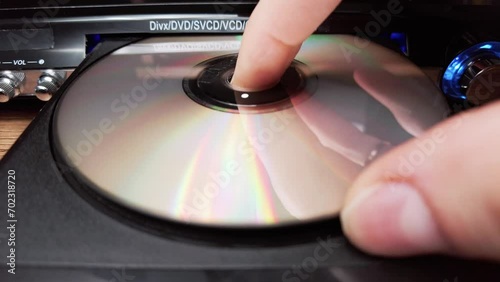 The compact disc is inserted into the DVD player. Male hand loads CD into a CD player tray close-up. Music, movies, or data recorded on a laser optical information storage medium. Loading Compact Disc photo