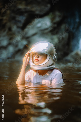 Fototapeta Naklejka Na Ścianę i Meble -  Young woman wearing an astronaut helmet sits with a fern tree.