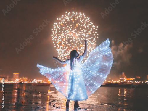 Woman in fancy dress with glowing butterfly wings During the firework festival