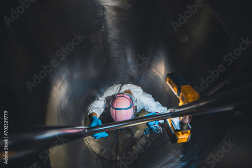Top view male climbs up the stairs into the tank stainless chemical area confined space