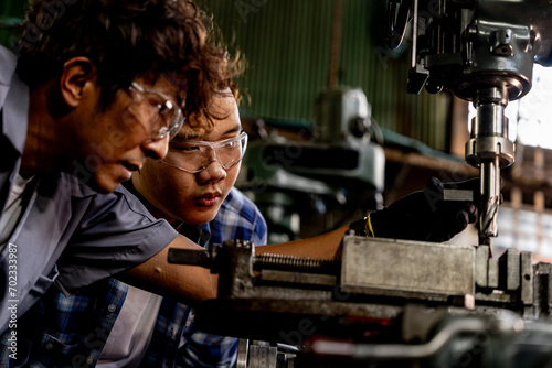 Asian worker in production plant drilling at machine. Professional worker near drilling machine on factory. finishing metal working internal steel surface on lathe grinder machine with flying sparks.