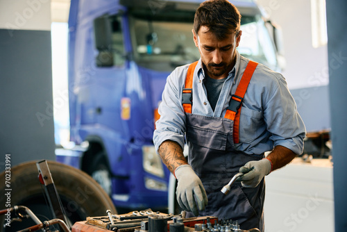 Mid adult mechanic working at truck repair shop. photo