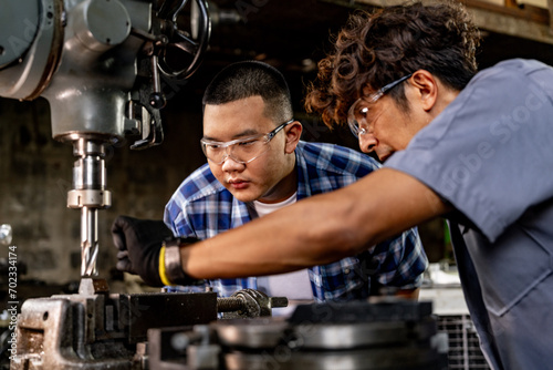 Asian worker in production plant drilling at machine. Professional worker near drilling machine on factory. finishing metal working internal steel surface on lathe grinder machine with flying sparks.