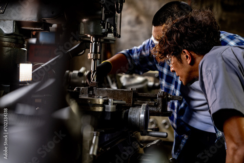 Asian worker in production plant drilling at machine. Professional worker near drilling machine on factory. finishing metal working internal steel surface on lathe grinder machine with flying sparks.