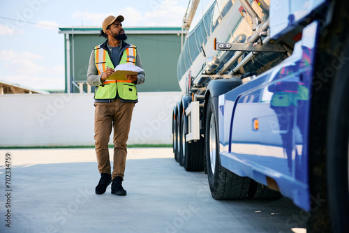 Φωτογραφία African American truck dispatcher inspecting vehicle on parking lot