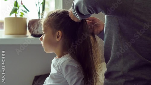 Mom braids her little daughter's long hair into pigtails at home. Shooting style is timelapse. Hair care. Motherhood. Happy childhood. Love and care. Home life. 4k footage