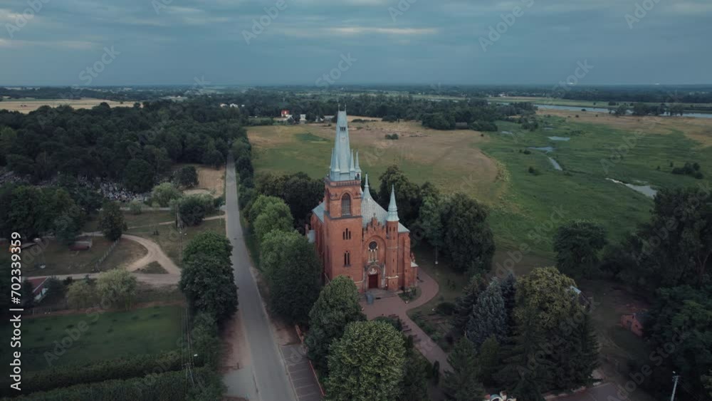 From an enchanting aerial perspective, the Neo-Gothic splendor of a Catholic Church emerges as a captivating symbol of spiritual beauty amidst the Polish countryside. The drone's view captures the arc From an enchanting aerial perspective, the Neo-Gothic splendor of a Catholic Church emerges as a captivating symbol of spiritual beauty amidst the Polish countryside. The drone's view captures the arc