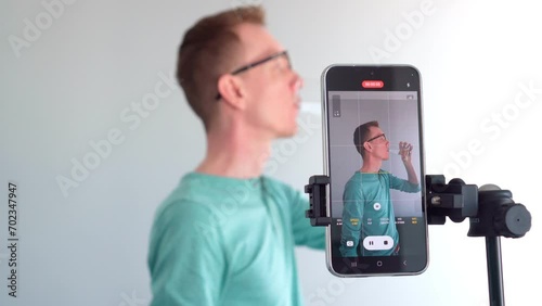 Male blogger takes video on his phone camera as he takes pills and drinks water. Blogging. Modern technologies. Professions online. Preparation for shooting. Devices and gadgets. 4k footage.