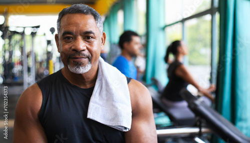 Portrait of smiling senior man with towel on shoulders in fitness center