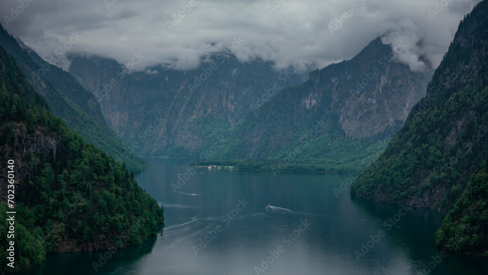 View to lake Königssee from above during moody weather, tourist boats on the water, mountains in background, Berchtesgaden Bavaria. View to lake Königssee from above during moody weather, tourist boats on the water, mountains in background, Berchtesgaden Bavaria.