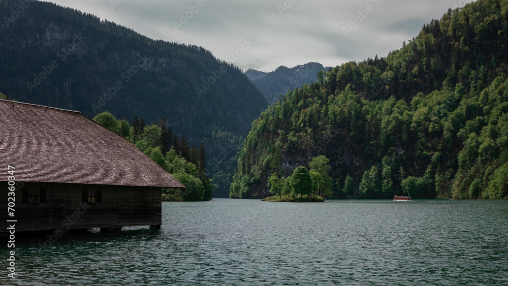 Lake Königssee with boathouse and tourist boat in Berchtesgaden Bavaria, mountains in background.