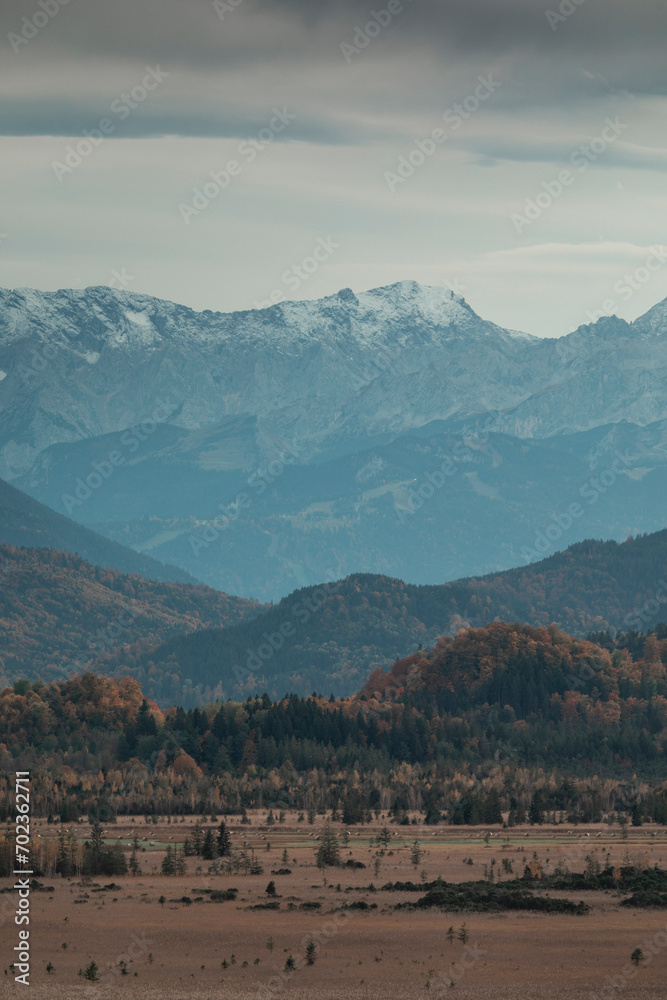 Panorama view over Murnauer Moos landscape with Bavarian Alp mountains during autumn, cloudy sky.