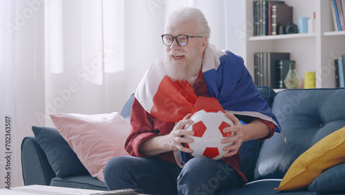 A happy grandpa celebrates the victory of the French football team, showing his joy as a supporter photo