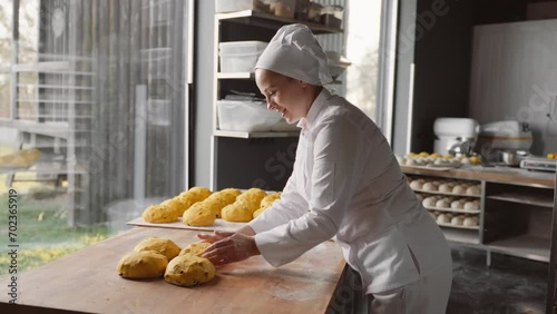 Female baker prepares raw bun before baking in oven